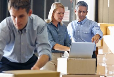executives in warehouse looking at computer